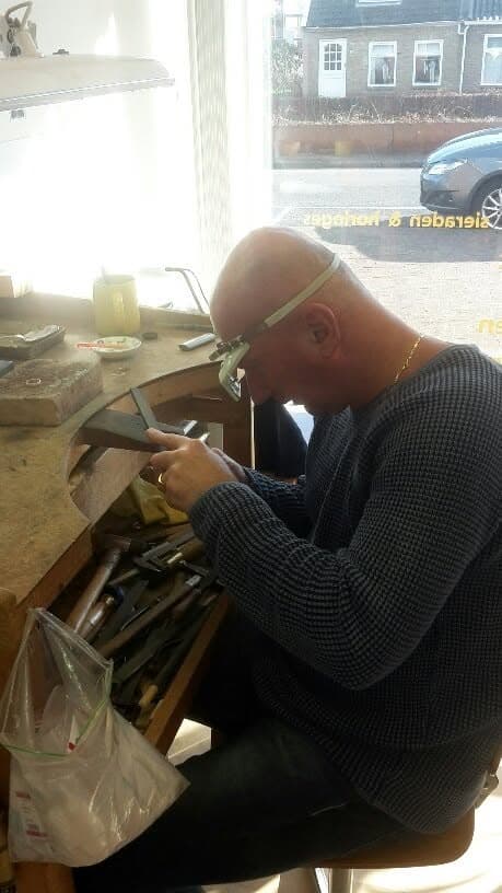 De goudsmid aan het werk aan de werkbank in het atelier