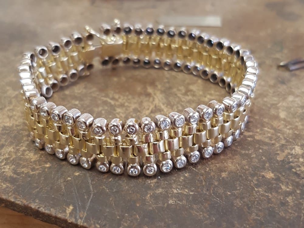 Opgerolde armband van geel- en witgoud met diamanten, op de werkbank