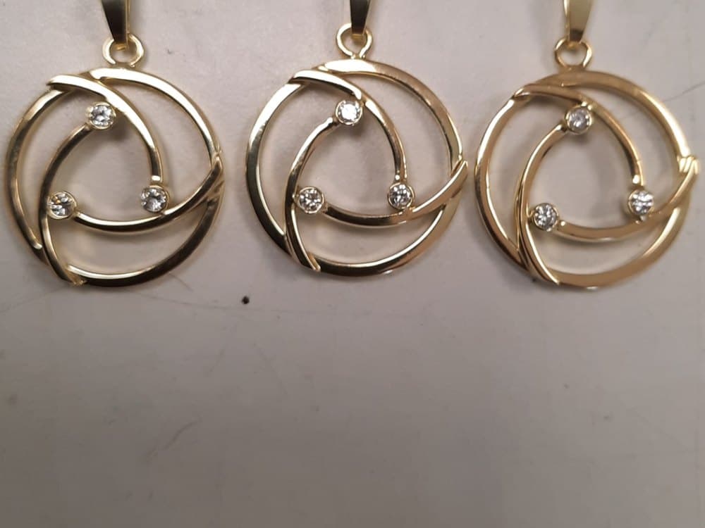 Drie gouden hangers in een spiraalvorm, elk met kleine diamanten
