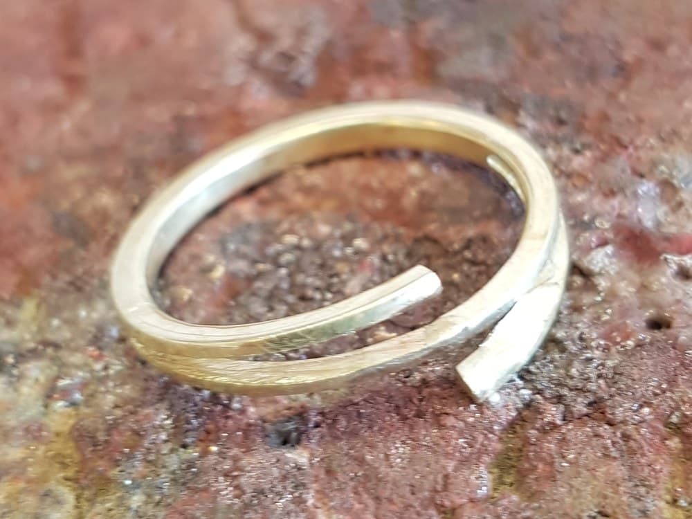 Een open gebogen ring van geelgoud met schuin afgevijlde uiteinden