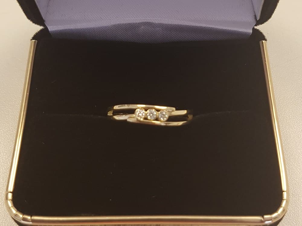 De nieuwe ring van geel- en witgoud met drie diamanten, in een geopend ringdoosje