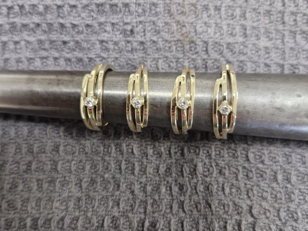 Vier gouden ringen met diamant naast elkaar op een stalen ringstok